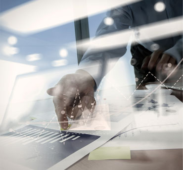 a man in a dress shirt gestures toward a graph that is printed out on a table.