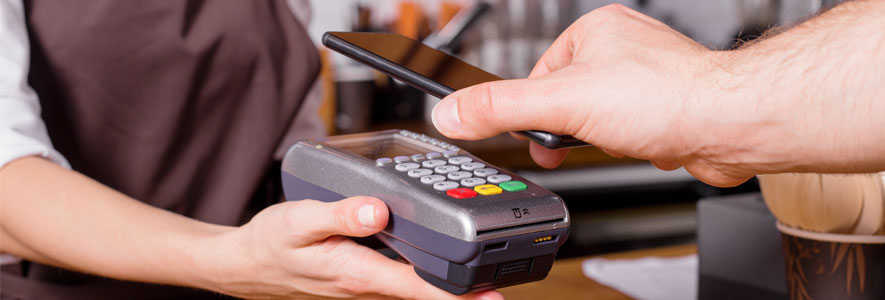 A customer pays with a mobile wallet by holding their phone up to the payment screen, showing the rapid evolution of payment processing.