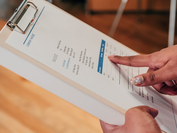 person pointing at an invoice on a clipboard