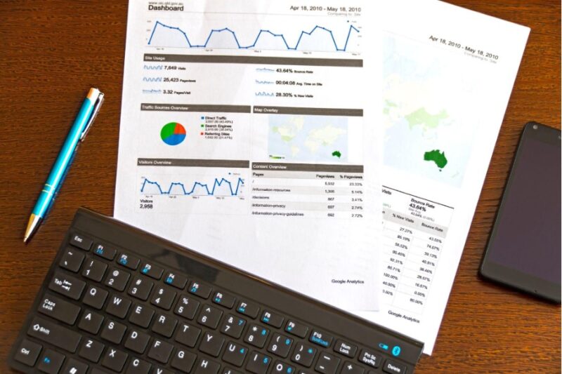 data sheets next to a keyboard and between a pen and a phone